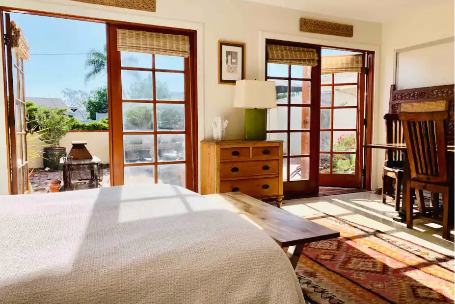 A bright bedroom with a bed, dresser, and patio access.
